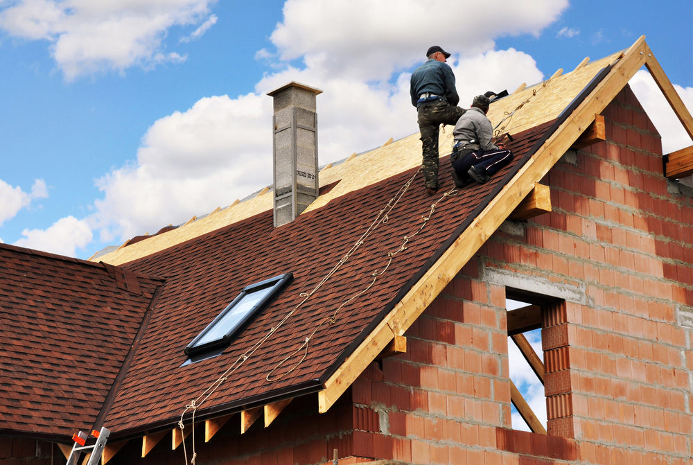 Professional roofers installing shingles on a house